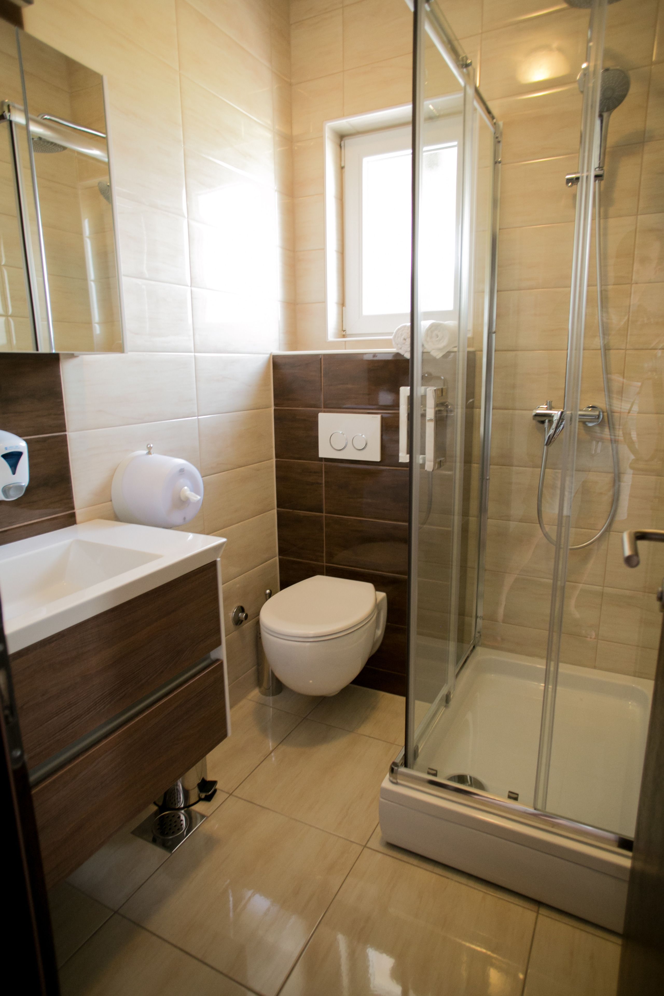 A bathroom with a glass-enclosed shower, a toilet, and a sink with a mirror above it.