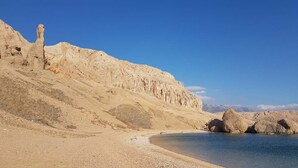 Paisaje desértico con cielo despejado, playa arenosa y formaciones rocosas.