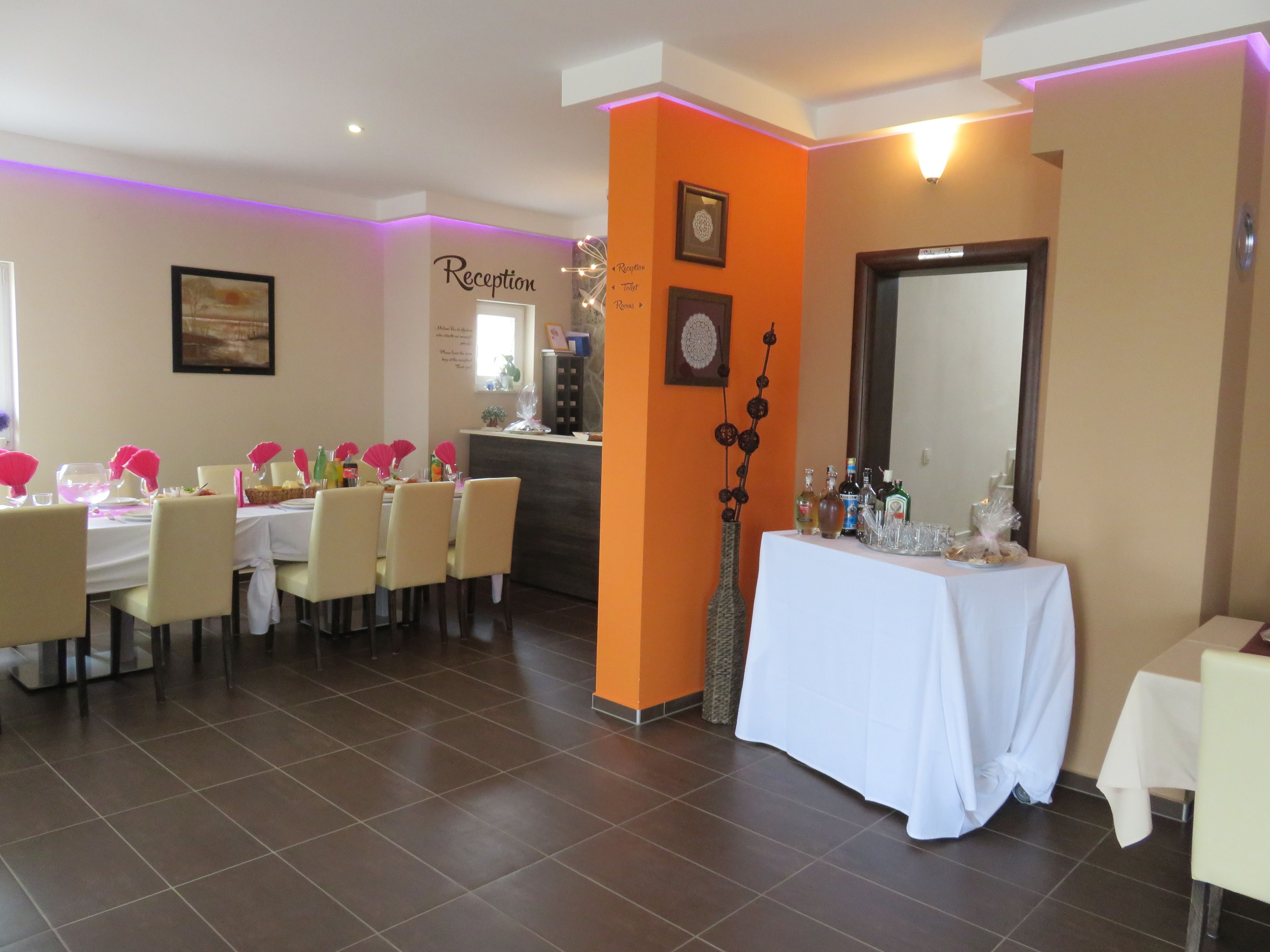 A dining area with a reception desk, a white table with a white tablecloth, and chairs.