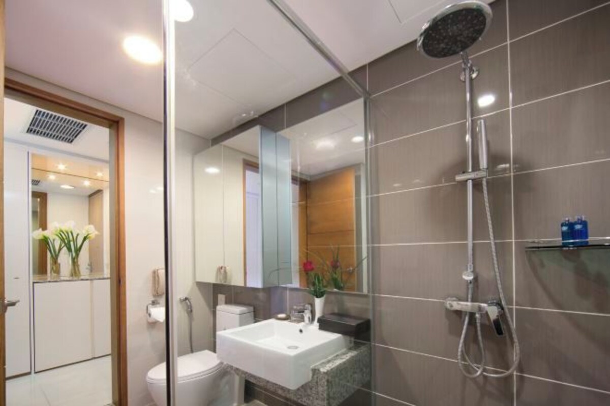 A modern bathroom with a glass shower enclosure, a white sink, and a mirror.