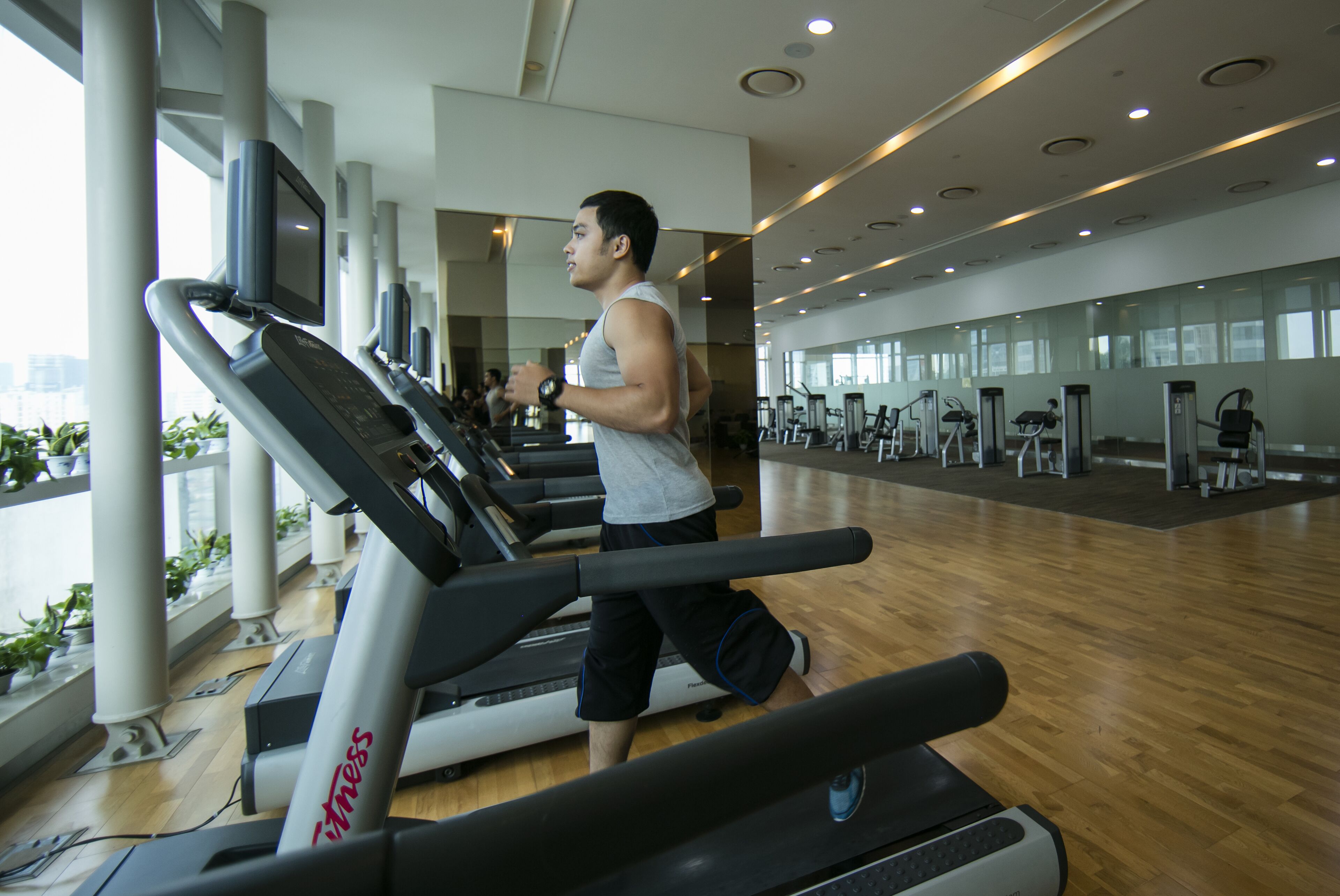A gym with treadmills, exercise equipment, and large windows.