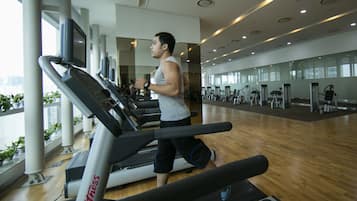 A gym with treadmills, exercise equipment, and large windows.