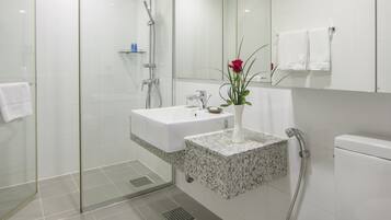 A modern bathroom with a glass-enclosed shower, a white sink with a marble countertop, and a toilet.