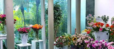 Une boutique de fleurs où l’on peut trouver une variété de plantes en pot et de fleurs présentées sur des tables et des étagères.