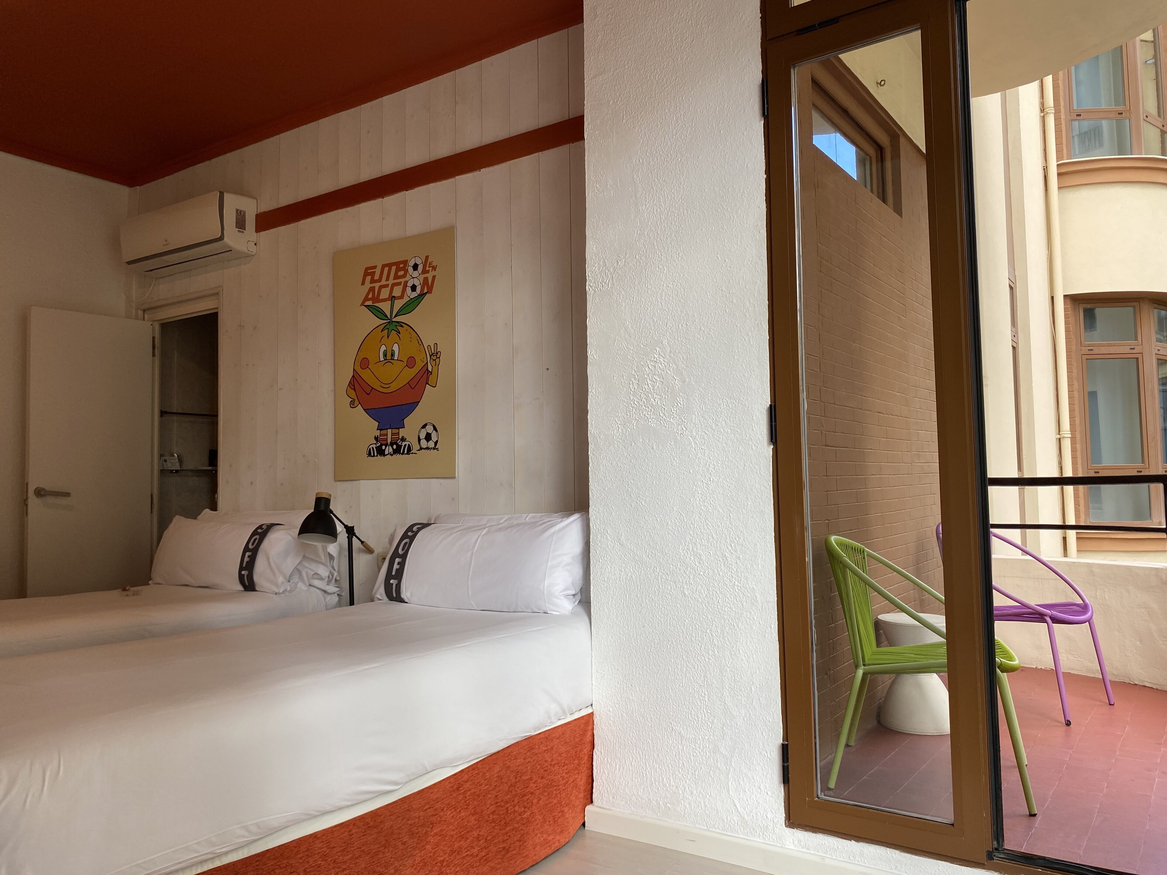 Ein Hotelzimmer mit Bett, Klimaanlage, einem Bild und Blick auf den Balkon.