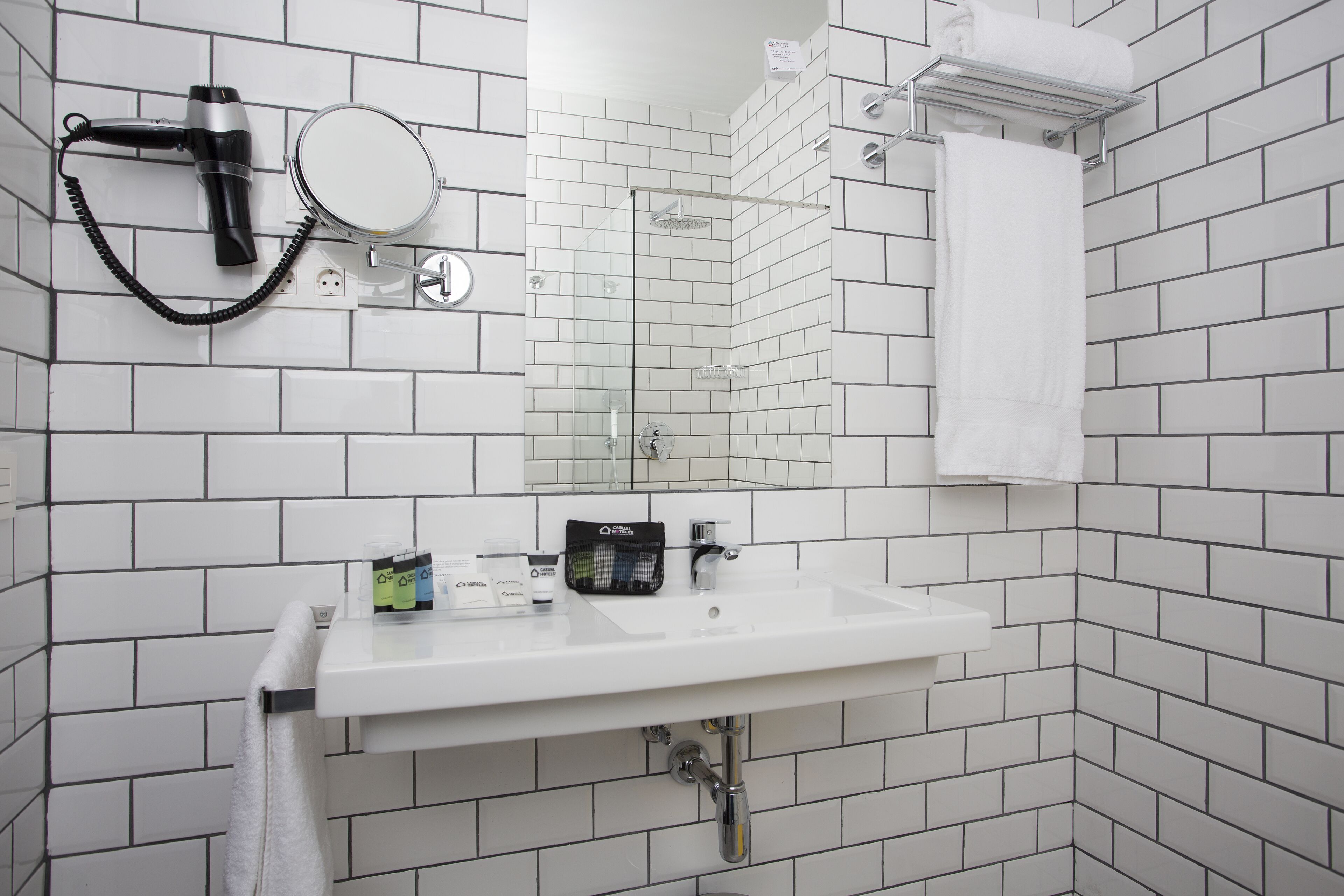 A bathroom with a white sink, a hairdryer, a mirror, and a towel rack.
