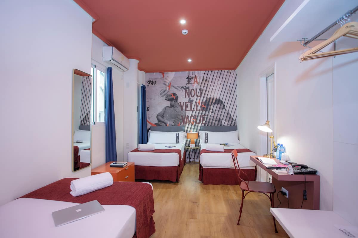 Une chambre d’hôtel avec deux lits, un bureau, une chaise, un miroir et une fresque murale.