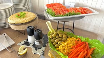 Una mesa de buffet con diversos alimentos, incluyendo ensalada, maíz, aceitunas y zanahorias.