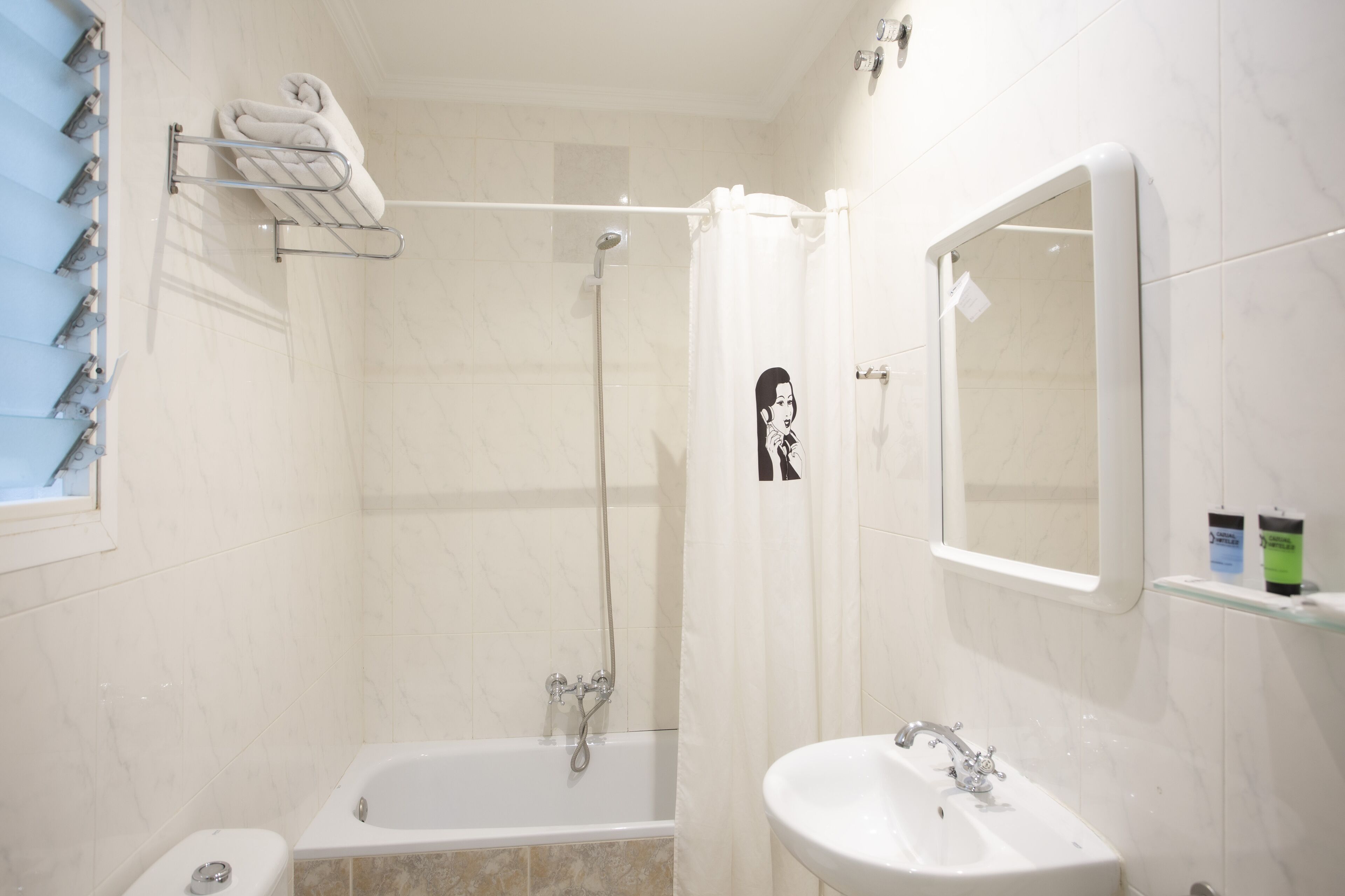 A bathroom with a bathtub, a shower, a sink, and a towel rack.