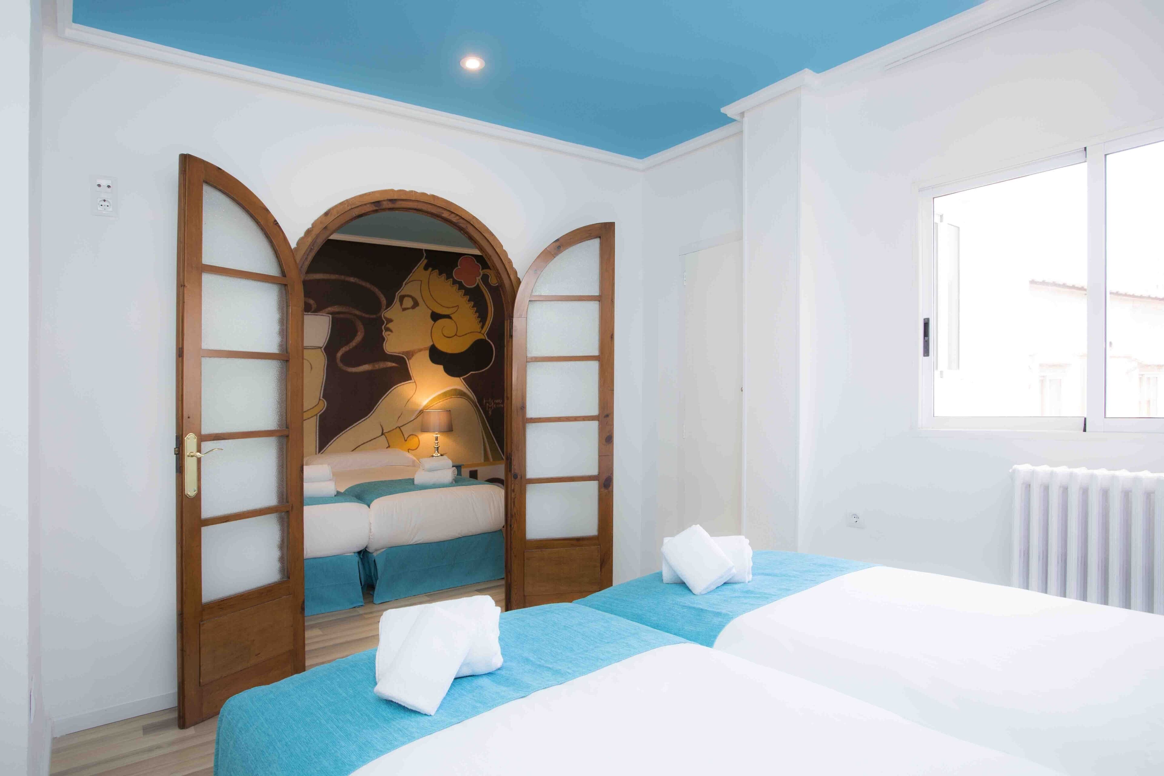 A hotel room with two beds, a large mirror, and a window.