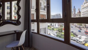 Una habitación con un ventanal grande, un escritorio y una silla.