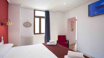Una habitación de hotel con una cama grande, una silla roja, un reloj y un televisor en la pared.