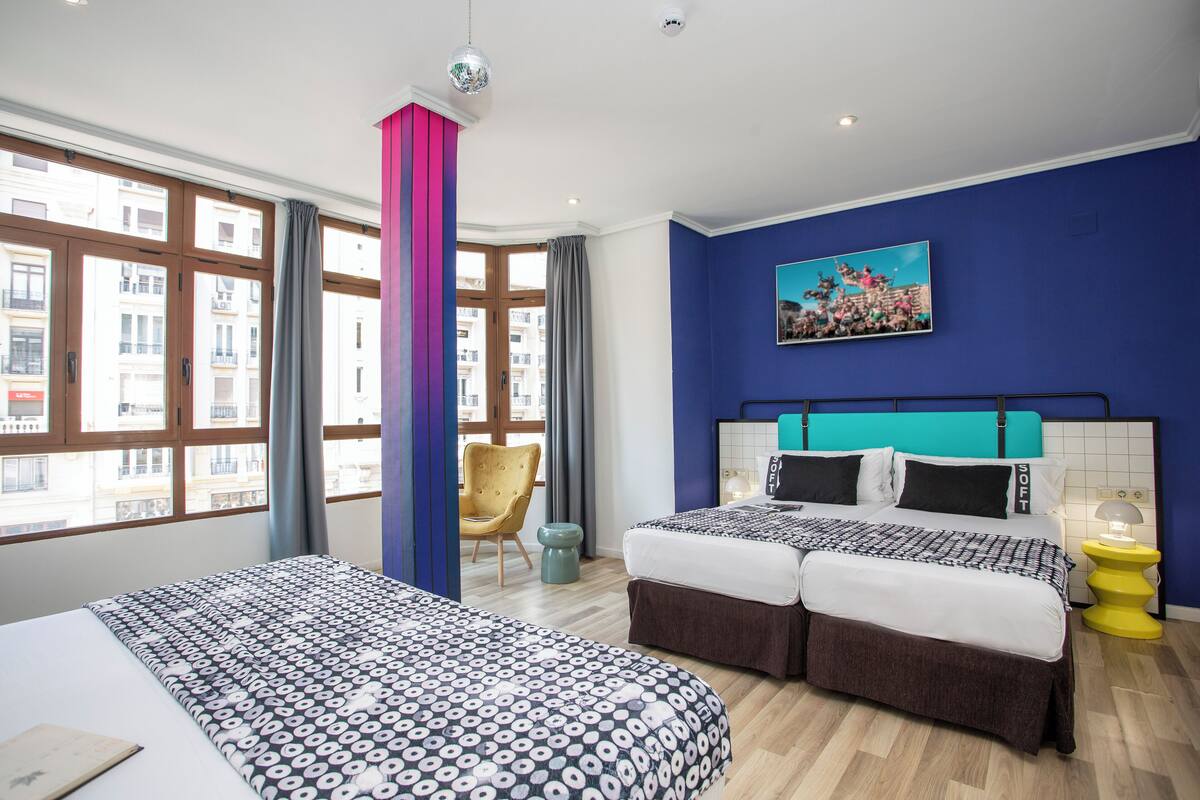 Une chambre d’hôtel avec deux lits, une grande fenêtre et une vue sur la ville.