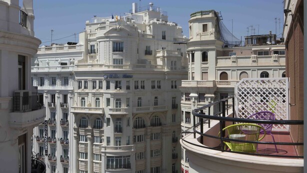 Un hotel de varios pisos con balcones y vistas a edificios cercanos.