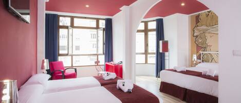 A hotel room with two beds, a desk, a chair, and a large window.