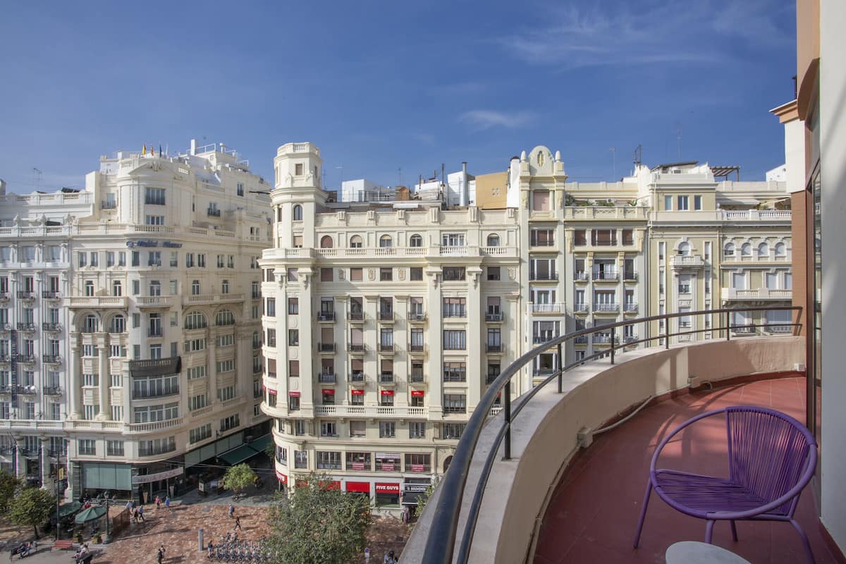 Une vue d’un immeuble à plusieurs étages, doté de balcons, sur lequel on aperçoit une chaise rouge.