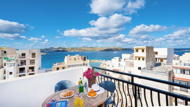Een balkon met een ontbijttafel met uitzicht op een kuststadsgezicht.