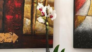Un quadro con forme astratte e un'orchidea in vaso.