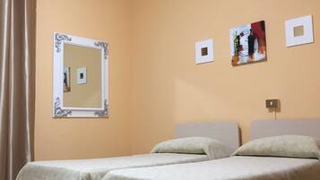 Ein Hotelzimmer mit zwei Betten, einem Spiegel und drei gerahmten Bildern an der Wand.