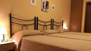 A double bed with a patterned bedspread, a nightstand with a lamp, and a wooden wardrobe. - Hotel Commercio (Campogalliano)