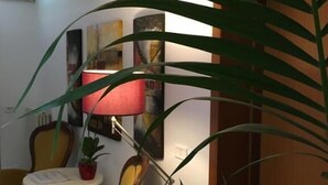 A room with a yellow armchair, a small round table with a lamp, and a potted plant. - Hotel Commercio (Campogalliano)