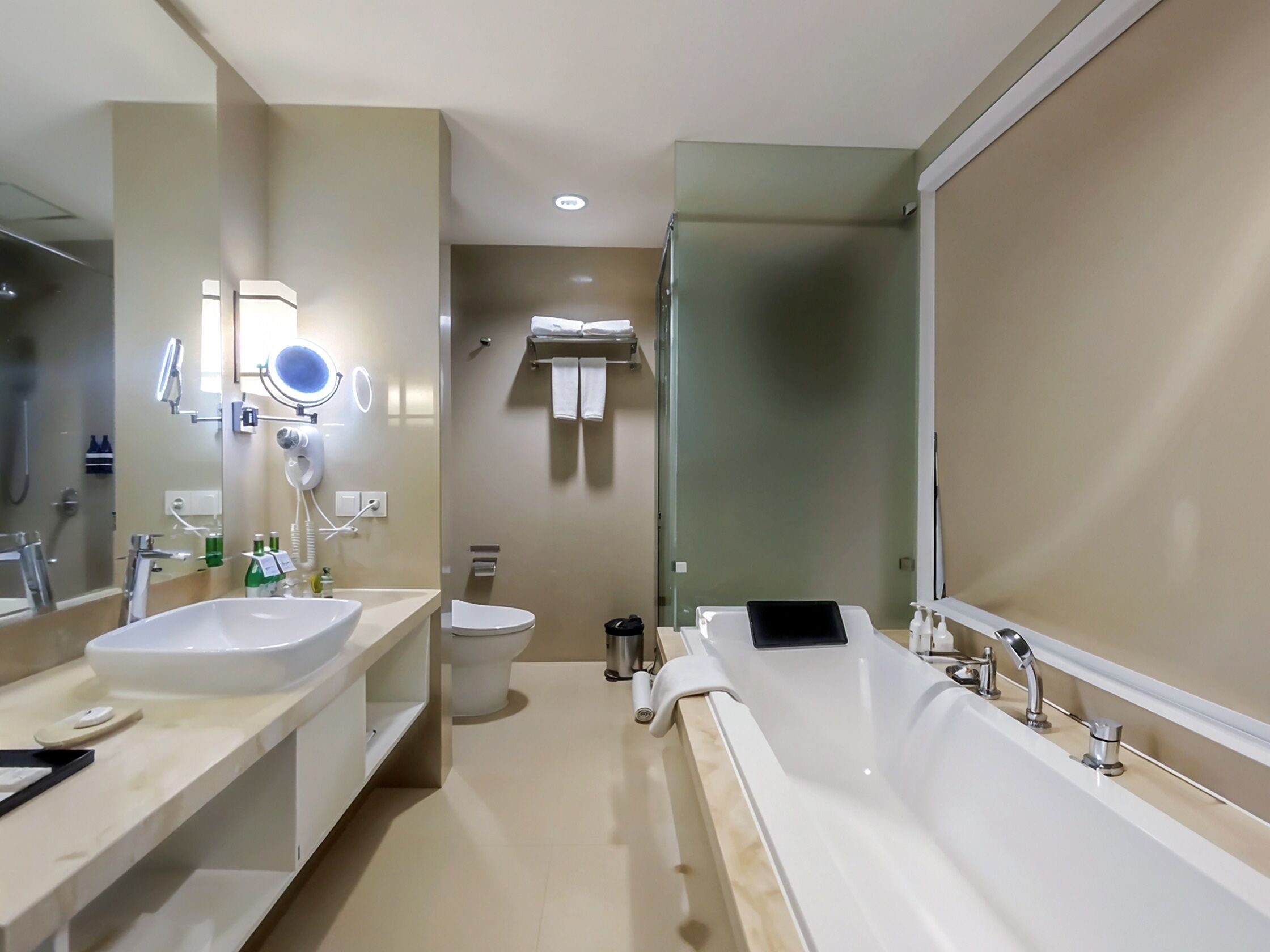 A modern bathroom with dual sinks, a large bathtub, a toilet, and a shower area.