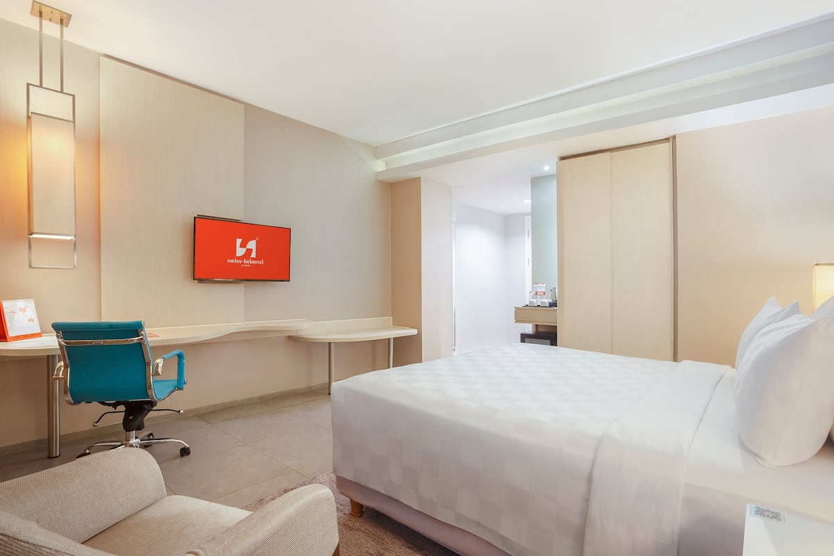 Une chambre d’hôtel comprenant un lit, un bureau, une chaise, une télévision et une armoire.