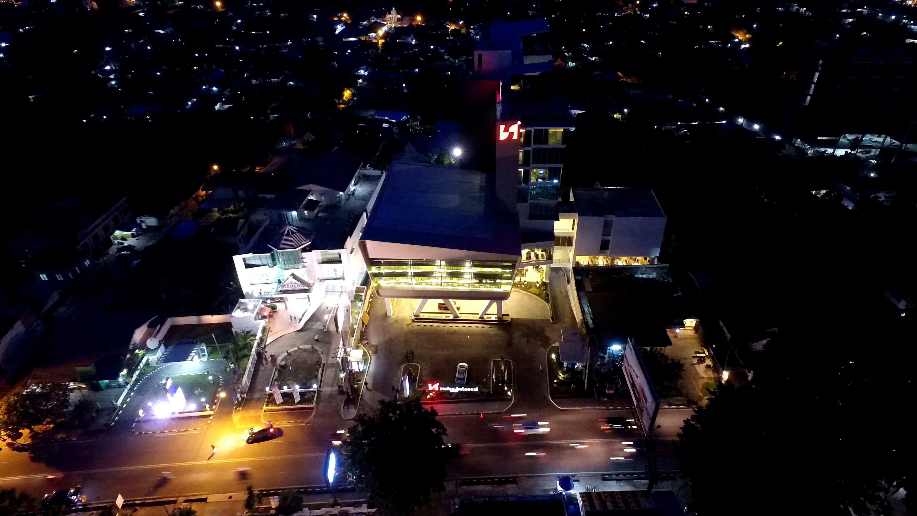 Un edificio de varios pisos con un letrero destacado, un corredor cubierto y un estacionamiento.