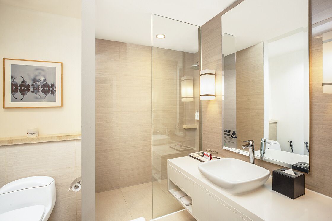 Un baño moderno con cabina de ducha de vidrio, un lavamanos blanco y una obra de arte enmarcada en la pared.