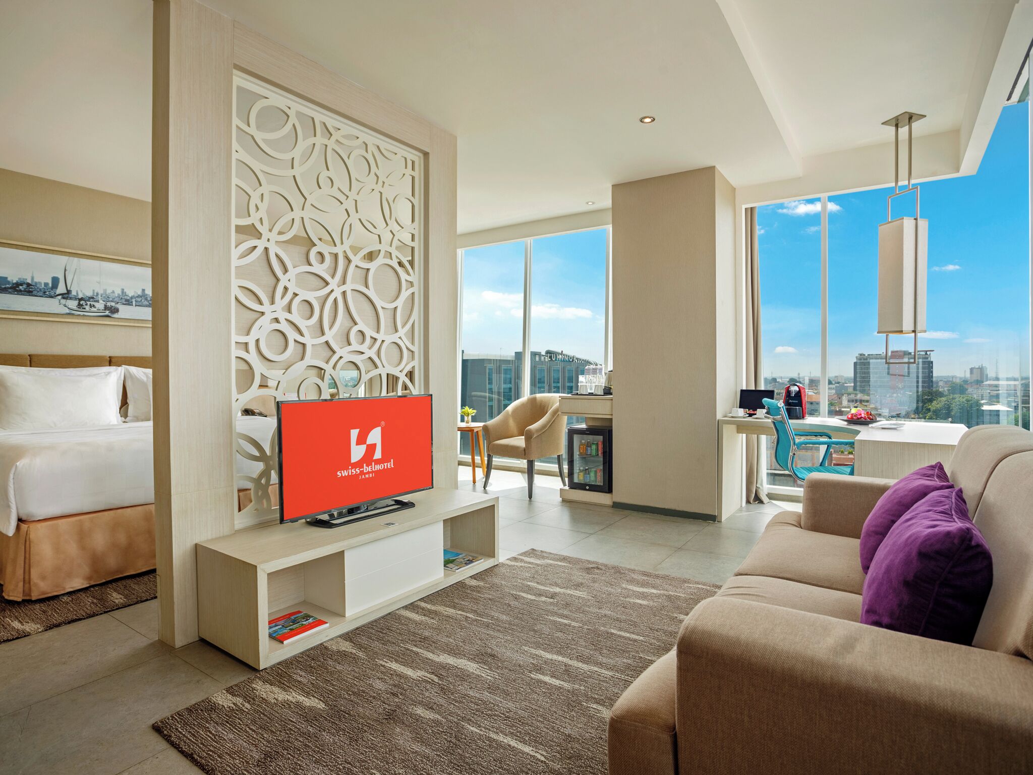 Une chambre d’hôtel moderne équipée d’un lit, d’une télévision, d’un coin salon et offrant une vue sur la ville.
