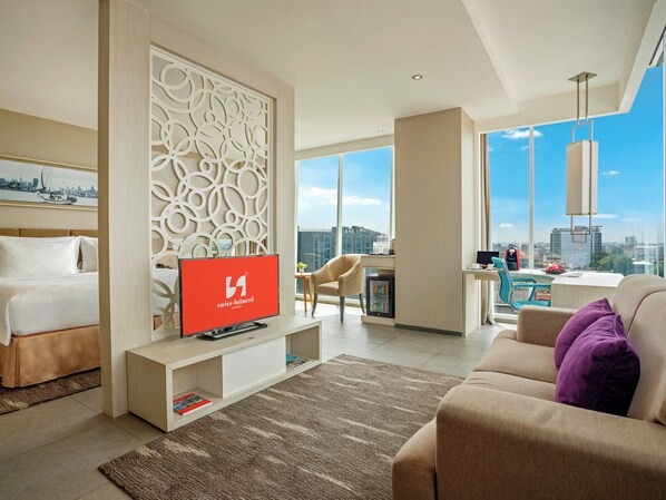 Une chambre d’hôtel moderne équipée d’un lit, d’une télévision, d’un coin salon et offrant une vue sur la ville.
