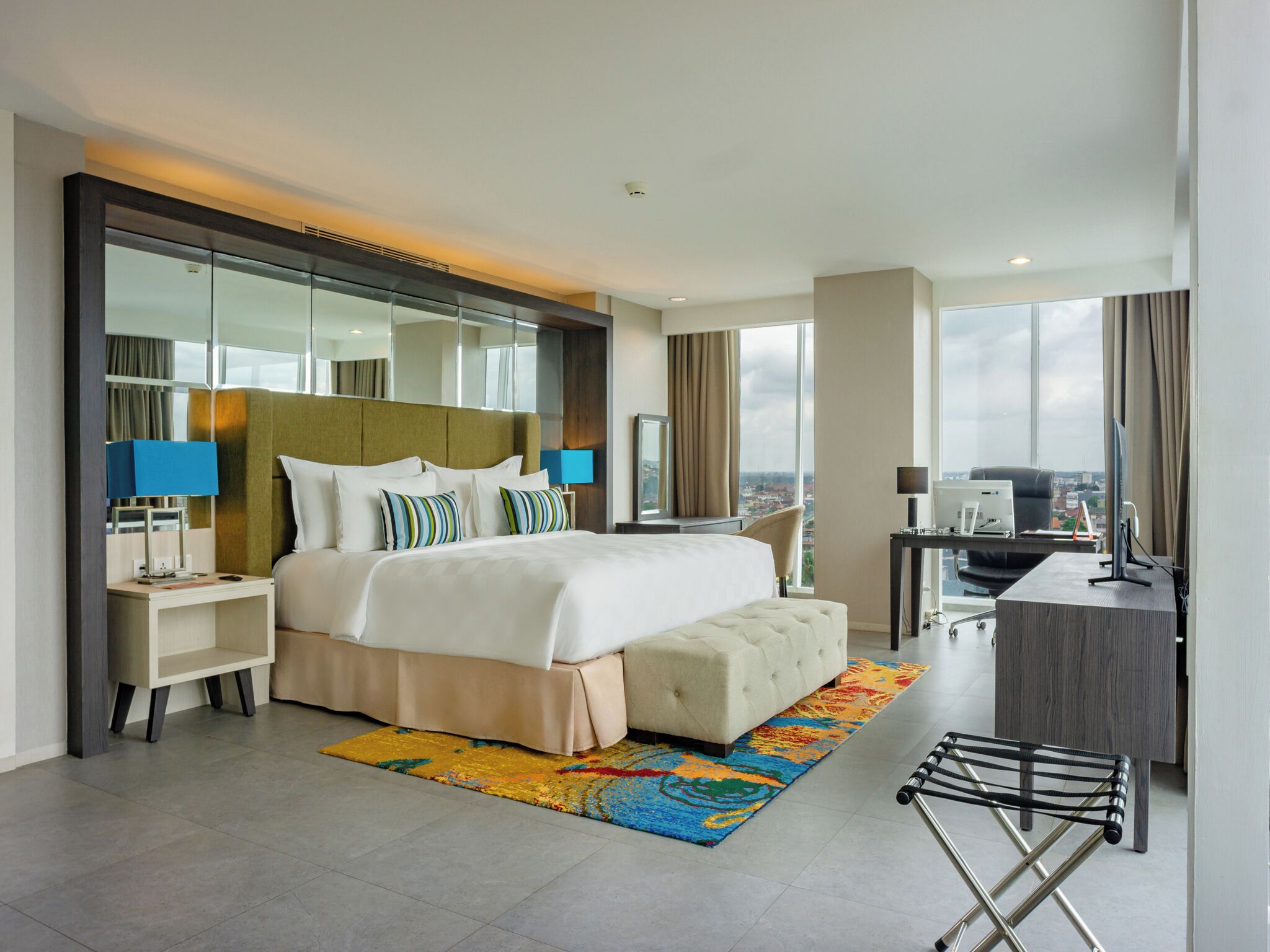 Een moderne hotelkamer met een groot bed, een bureau, een stoel en uitzicht op de stad.