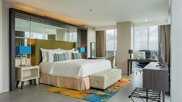 A modern hotel room with a large bed, a desk, a chair, and a view of the city.