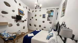 A bedroom with a bed, a chair, a TV, and a lamp. - Hotel Rural Villa Hermigua (Hermigua)