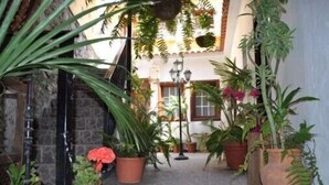 A narrow stone pathway flanked by potted plants and a traditional lamp post, leading to a building with a window and a door. - Hotel Rural Villa Hermigua (Hermigua)