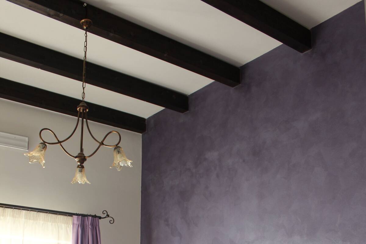 A bedroom with a bed, a chandelier, and a window with curtains.