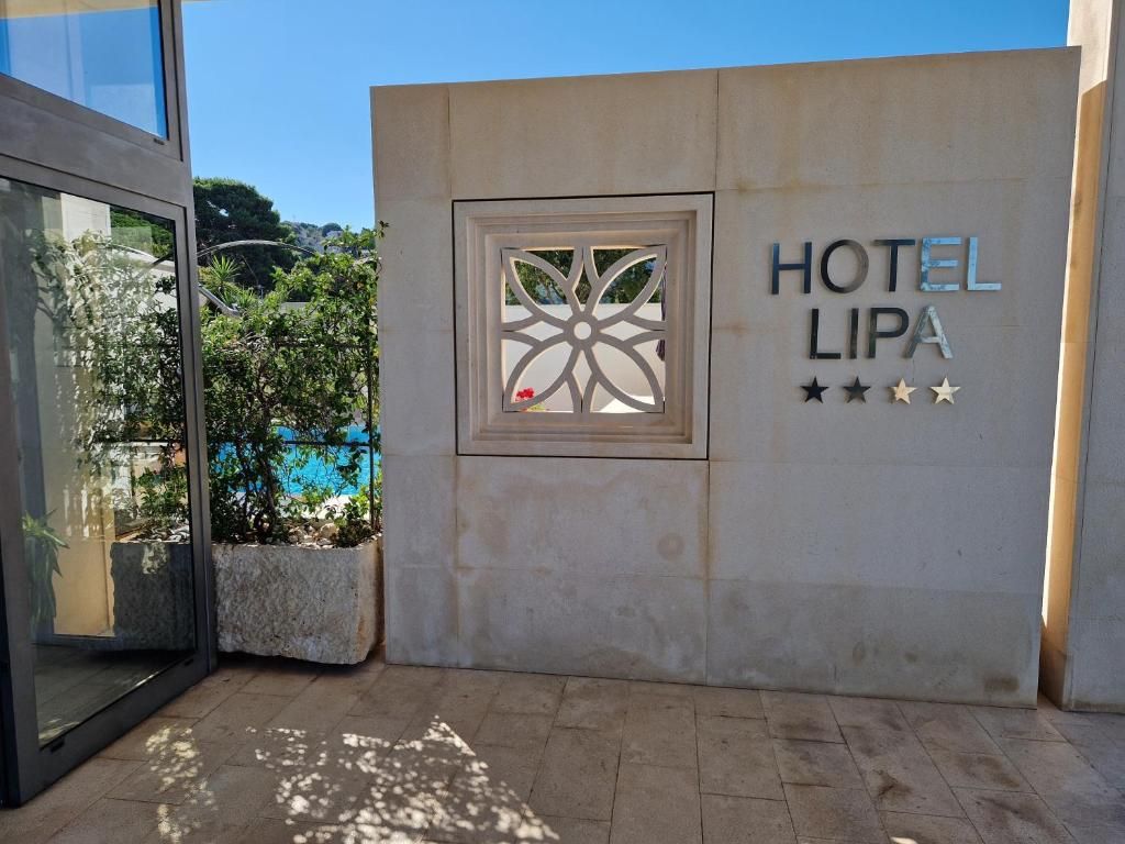 L’entrée d’un hôtel, avec une enseigne indiquant « HÔTEL LIPA » et une fenêtre décorative.