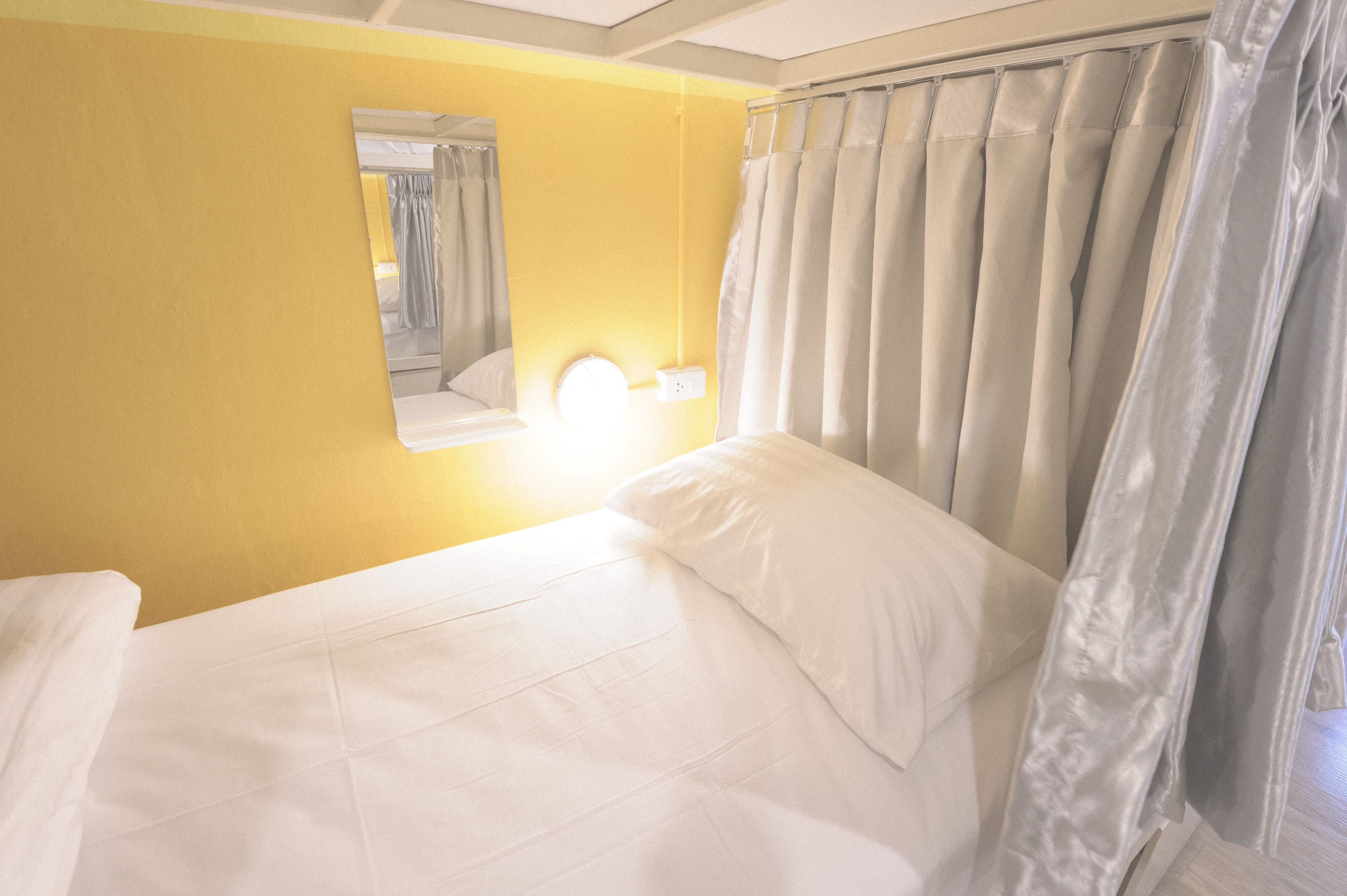 A hotel room with a bed, a mirror, and curtains.