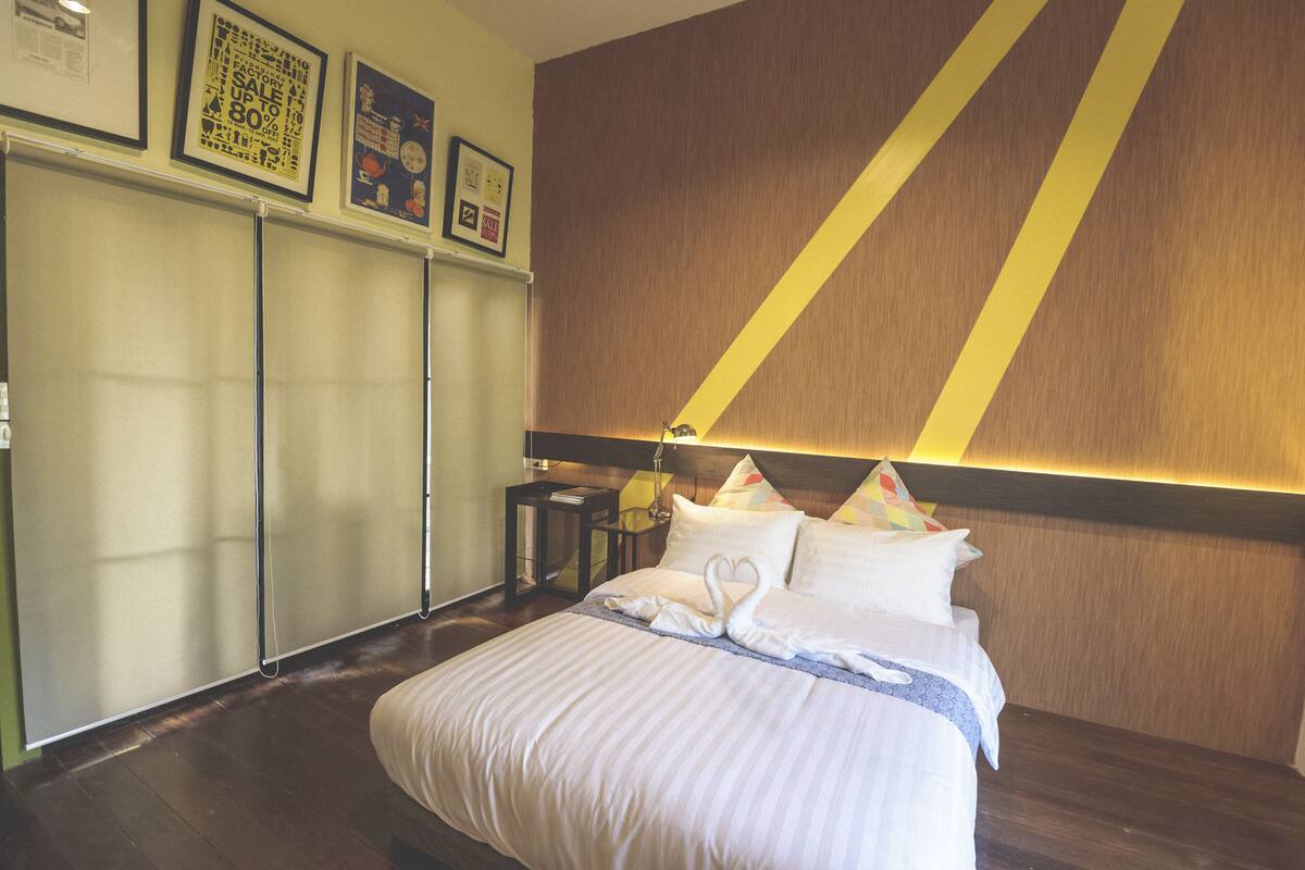A hotel room with a bed, a nightstand, a lamp, a wardrobe, and framed pictures on the wall.
