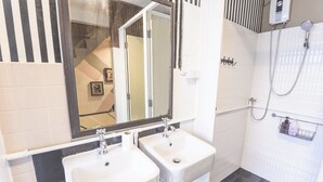 A bathroom with two sinks, a mirror, a shower, and a towel rack. - Bharani Hostel (Bangkok)