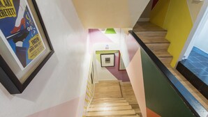 A staircase with wooden steps, colorful walls, and a framed poster on the left. - Bharani Hostel (Bangkok)