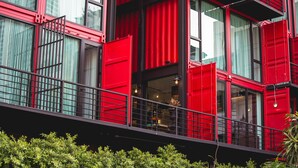 A modern building with red and black exterior walls, large windows, and a balcony with a railing. - Sleep Box Sukhumvit 22 (Bangkok)