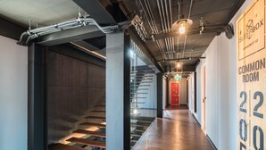 A modern hallway with exposed pipes, a staircase, and a sign for a common room. - Sleep Box Sukhumvit 22 (Bangkok)