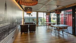 A modern interior with a mural, wooden flooring, and a dining area with tables and chairs. - Sleep Box Sukhumvit 22 (Bangkok)