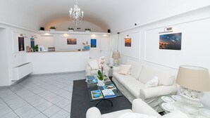 Een moderne hotellobby met een receptiebalie, een zithoek met een bijzettafeltje en een kroonluchter.