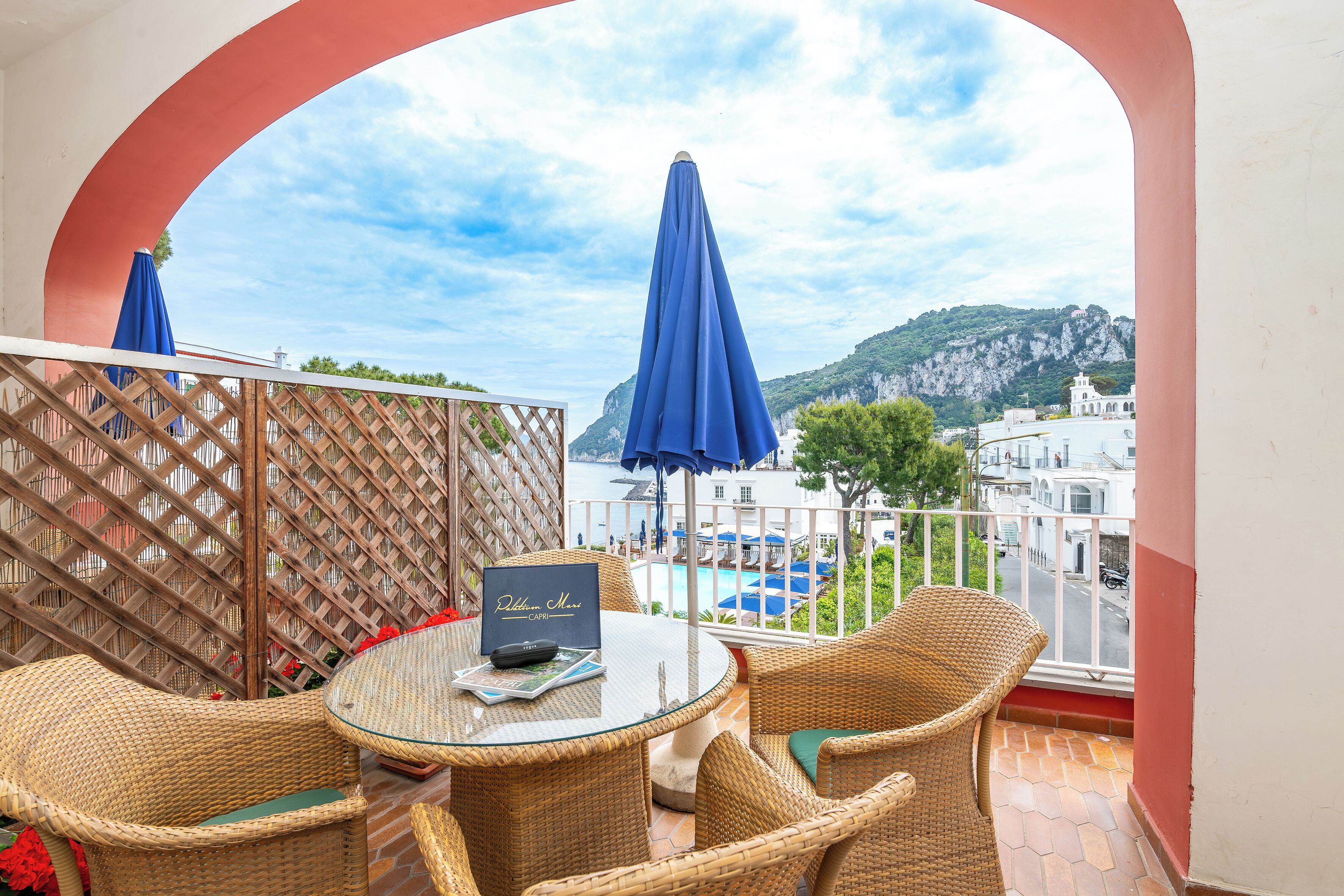 A balcony with wicker furniture, a glass table, and a menu stand.
