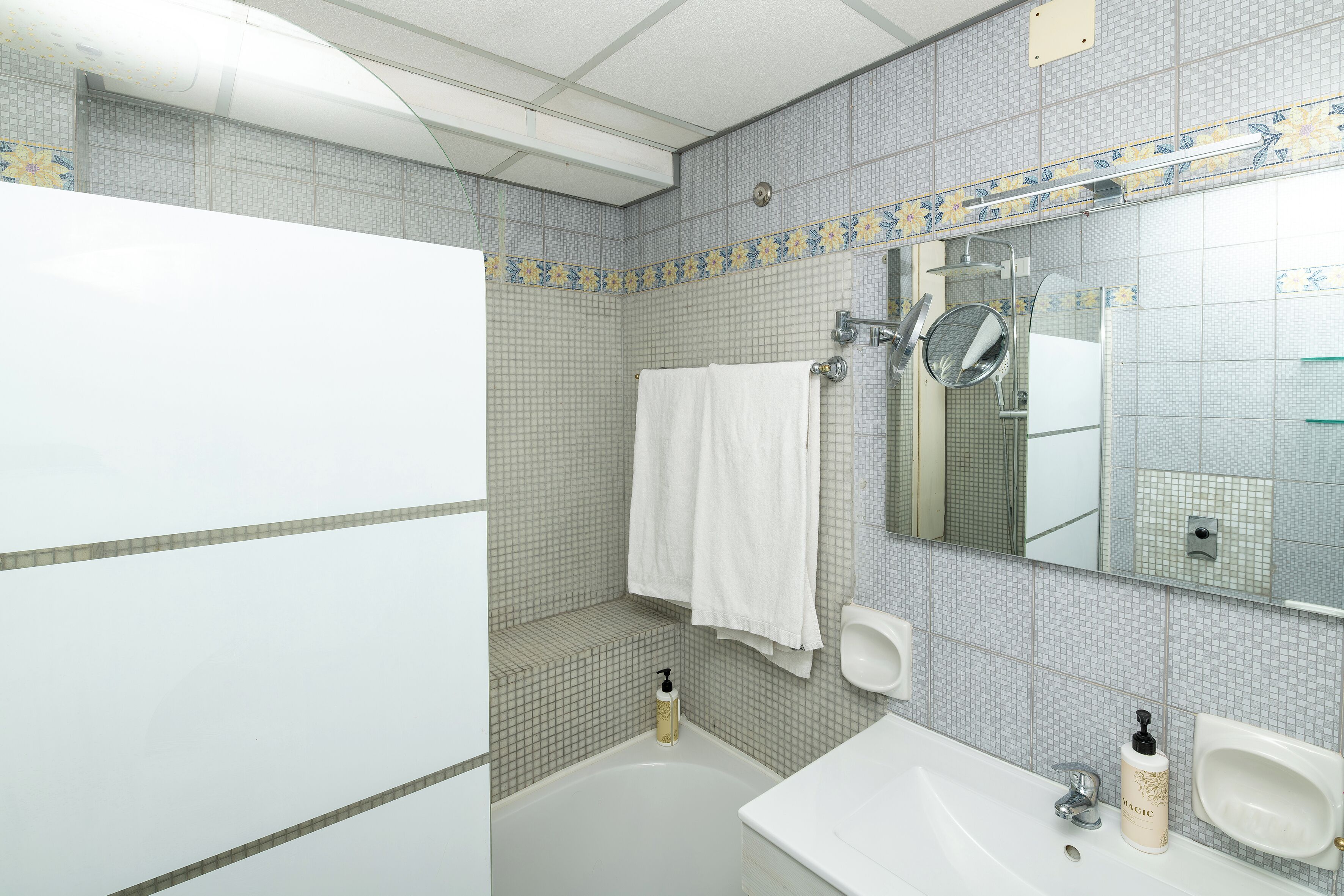 A bathroom with a bathtub, two sinks, a mirror, and a towel rack.