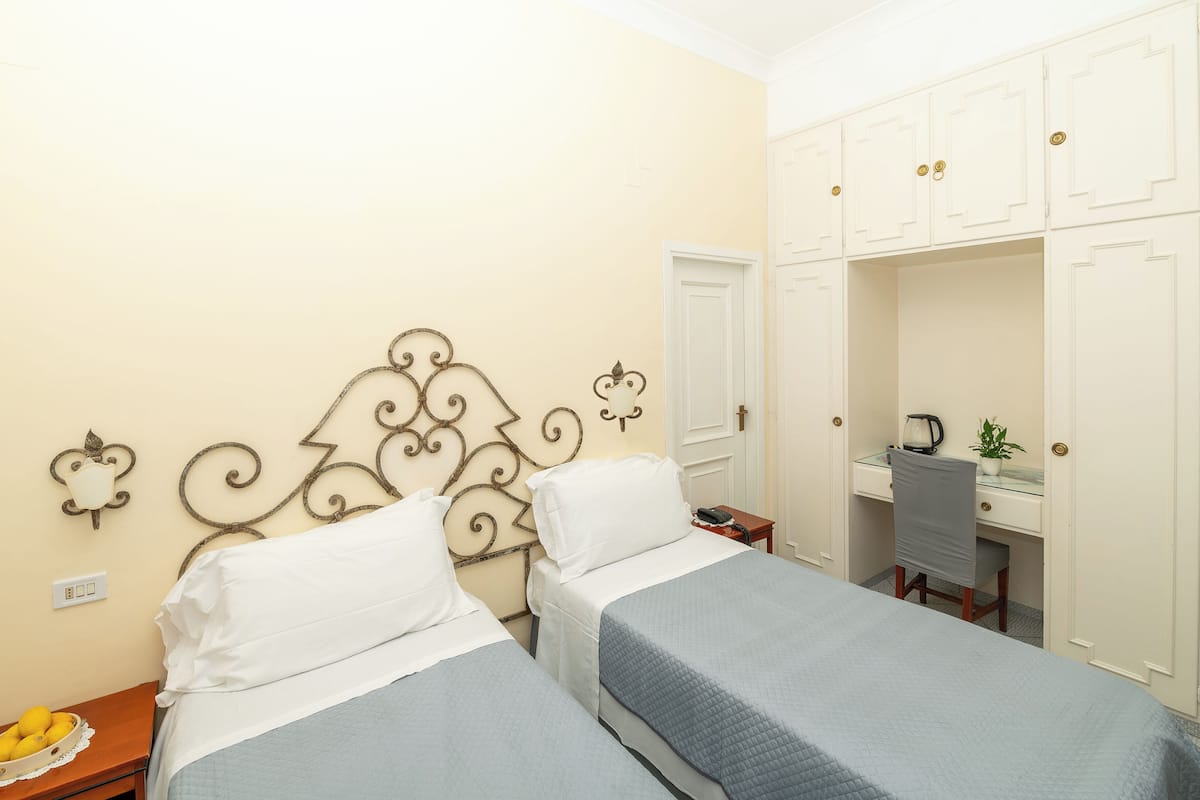 Una habitación de hotel con dos camas, un escritorio, una silla y un armario.