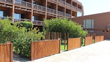 A multi-story building with balconies and a wooden fence in front.