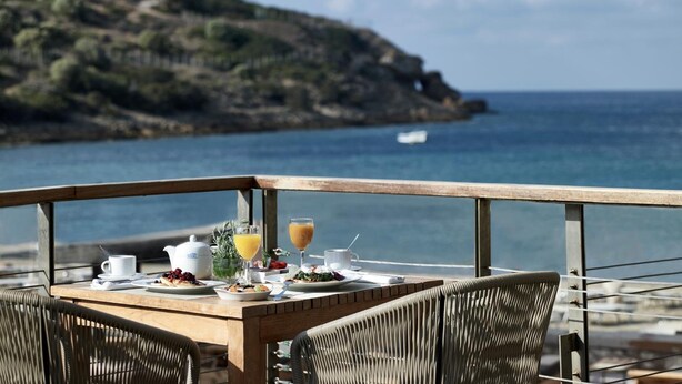 A dining table with breakfast items and a view of the sea. - Aegeon Beach Hotel (Lavreotiki)